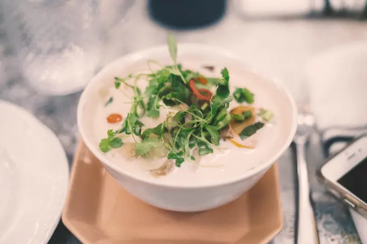 Close-up photo of a bubbling pot of soup or stew, with steam rising gently from the surface, symbolizing the warmth and nourishment of slow-cooked meals prepared with love and care.